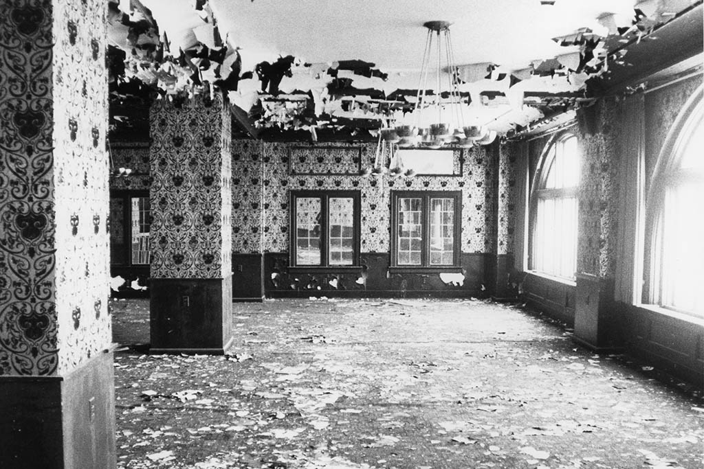 Graham Plaza interior prior to the renovation – paint pealing off the ceiling, pigeon manure everywhere, striped wallpaper, bunched up carpet, and more.