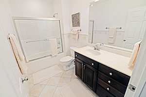 This spacious second bathroom has a neutral color palette of whites and creams and a complementary title floor.